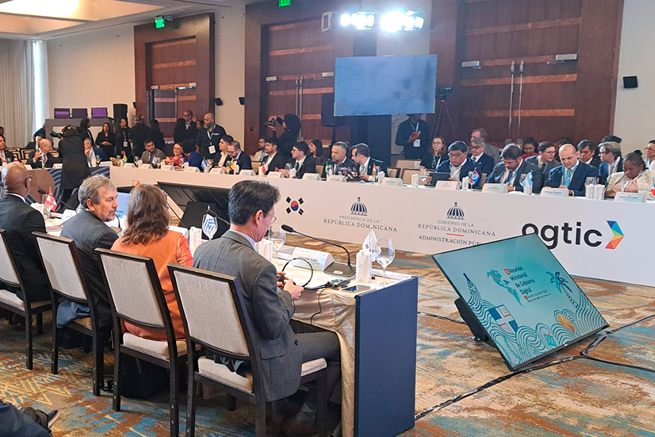 Personas participando del evento en la sala, sentados en una mesa en forma de u.