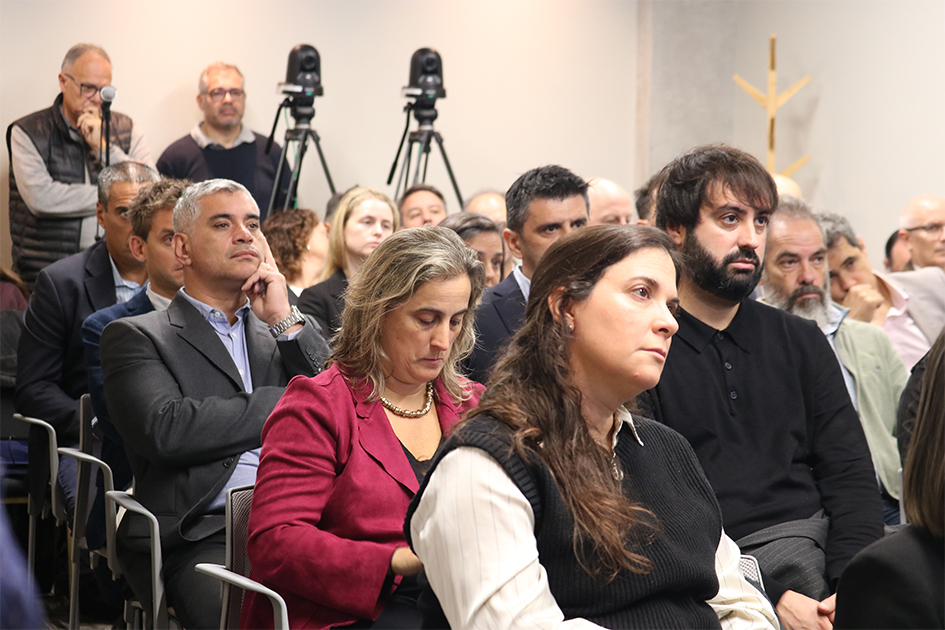 Personas en sala mirando hacia adelante y escuchando con atención