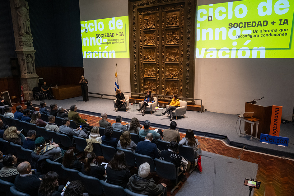 Foto: Intendencia de Montevideo. Imagen modificada con herramientas de IA generativa. Personas en sala mirando el panel de apertura integrado por Zubillaga, Repetto y Apolaro.