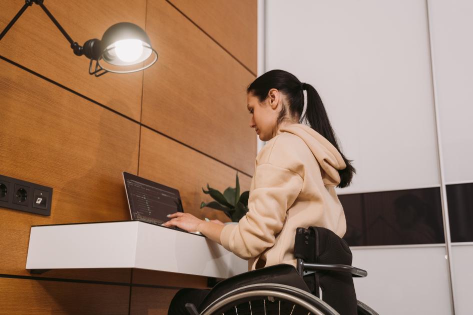 Una persona en silla de ruedas usa una laptop. Una persona en silla de ruedas usa una laptop.