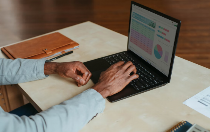 manos en teclado, pantalla con datos estadísticos