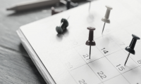 Gestión del conocimiento Hoja de calendario sobre mesa de madera con días señalados.
