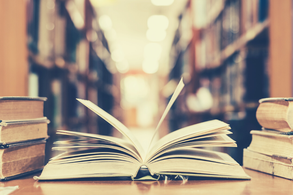 Actualización del TOCAF Imagen de biblioteca con escritorio, libro abierto sobre ella y libros cerrados.