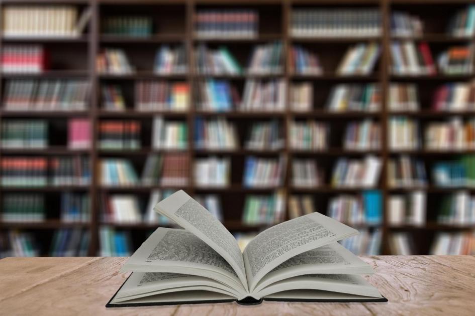Cursos disponibles en octubre Libro abierto sobre mesa con biblioteca de fondo