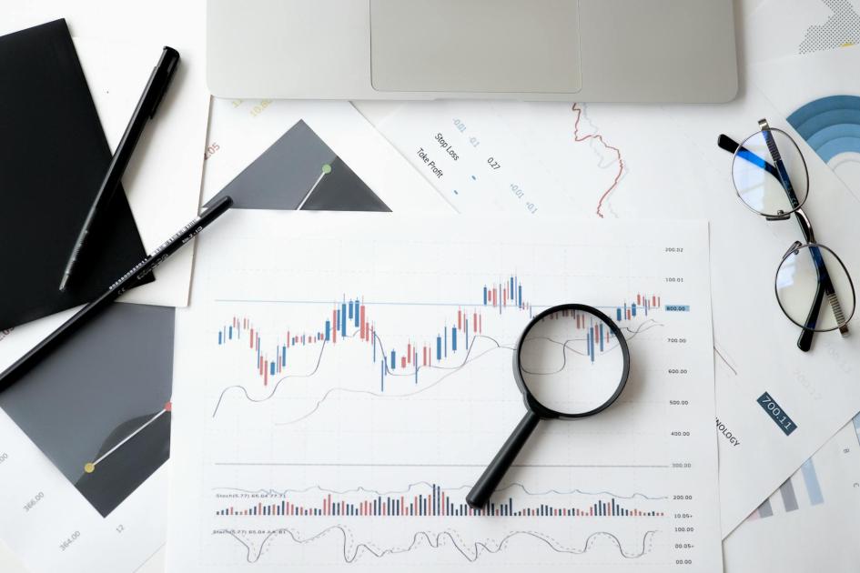 Transparencia Lupa, bolígrafos y lentes sobre documentos con gráficos