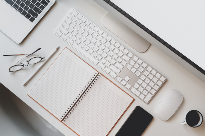 Cursos de capacitación Escritorio con distintos elementos sobre el: agenda, taza de café, lentes, teclado, etc.
