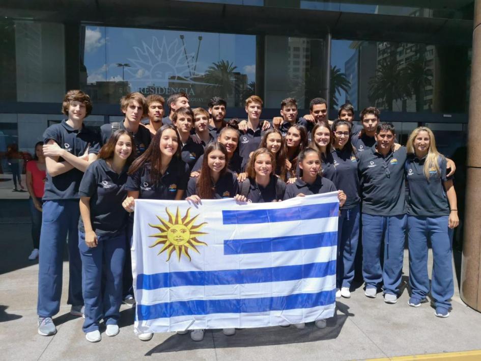 foto con la bandera uruguaya de parte de la delegación de deportitas a las afuera de la torre ejecutiva