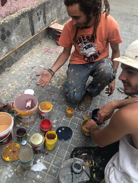 artistas en la vereda en el momento de realizar el mural