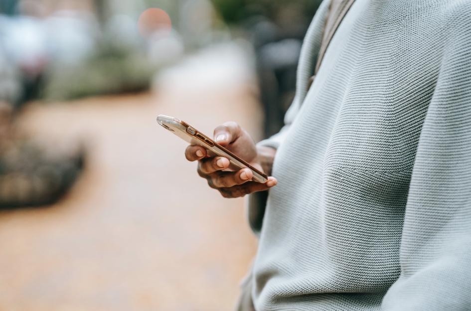 Manos de persona con un celular Una persona de perfil con un celular en su mano