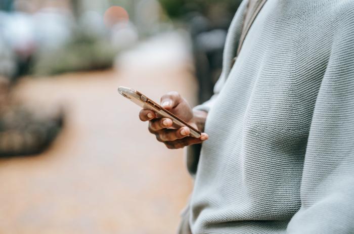 Una persona de perfil con un celular en su mano