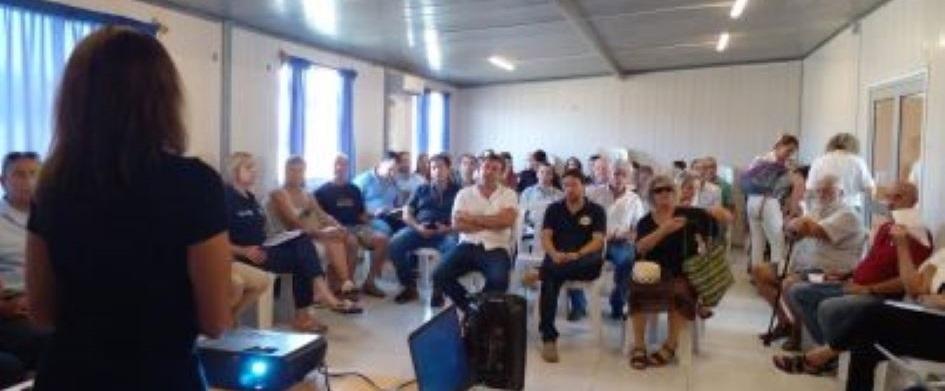 Mujer parada hablando a un grupo de personas sentadas en una sala