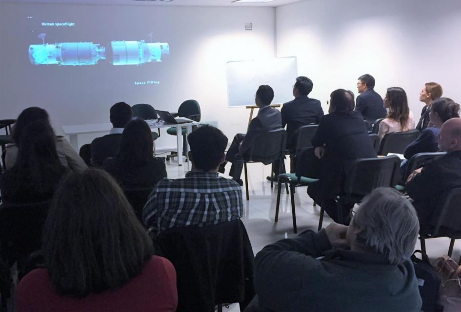 Sala multifunción, participantes observando pantalla con presentación.