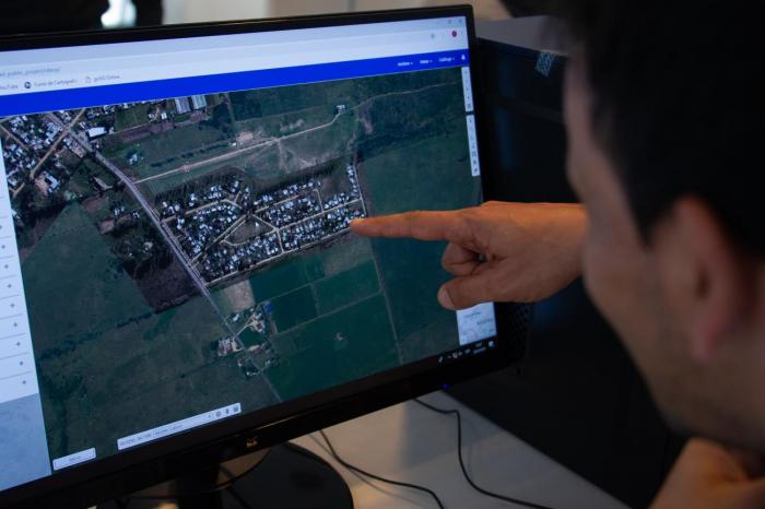 Geoportal persona indicando en la pantalla y otra observando. Se ve foto aérea.