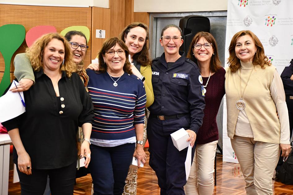 Entrega de diplomas a los participantes del curso Una cadete de policía, visitiendo su uniforme, posa con las docentes y su diploma