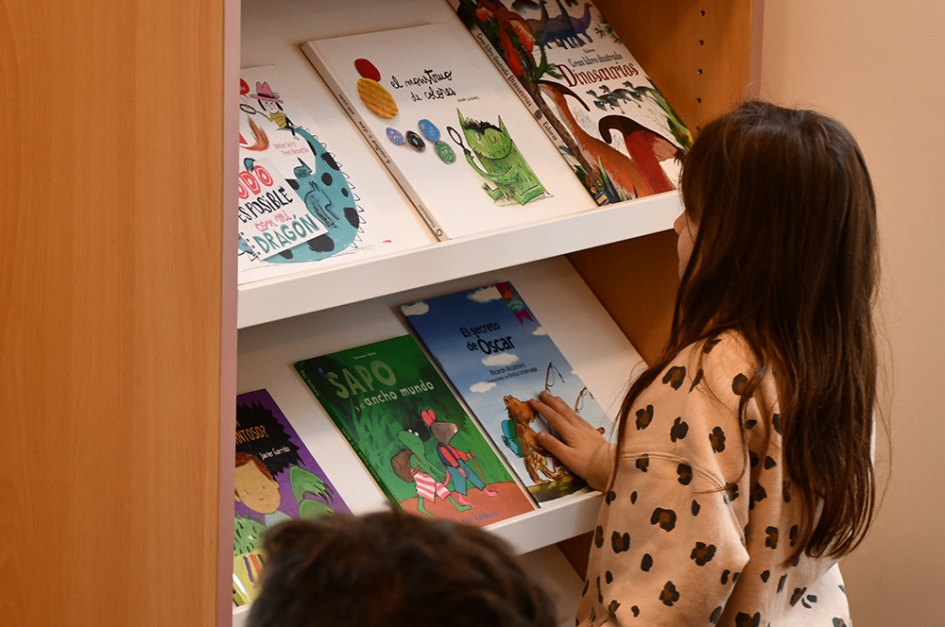 actividad de promoción de la lectura en la INDDHH niña mirando libros en un estante