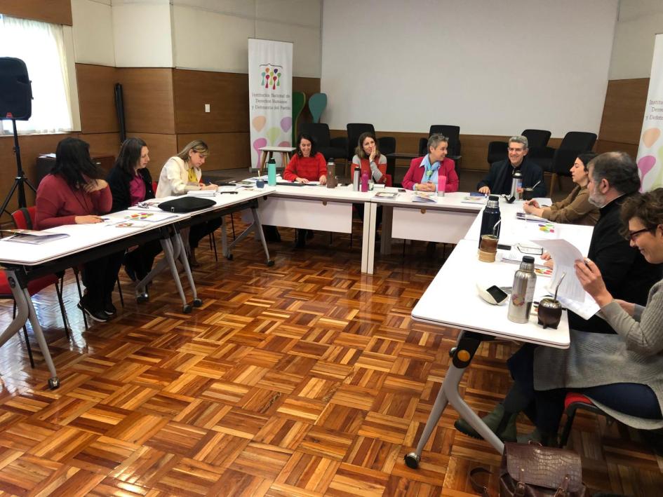 Grupo de trabajo en su primera reunión Grupo de trabajo en su primera reunión, sentados en torno a una mesa en U y pantalla frontal