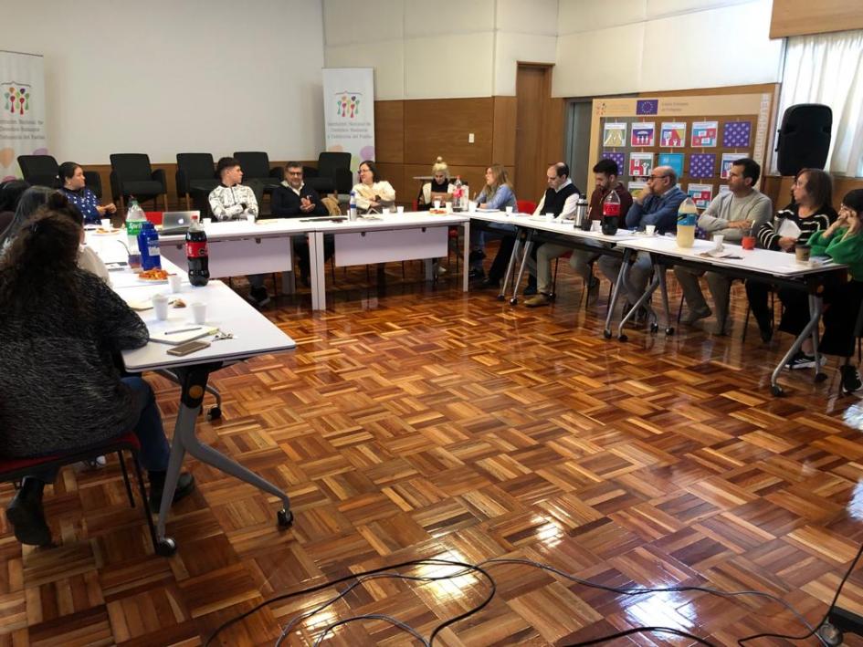 Integrantes de la Institución sentados en torno a una mesa intercambian durante el taller.