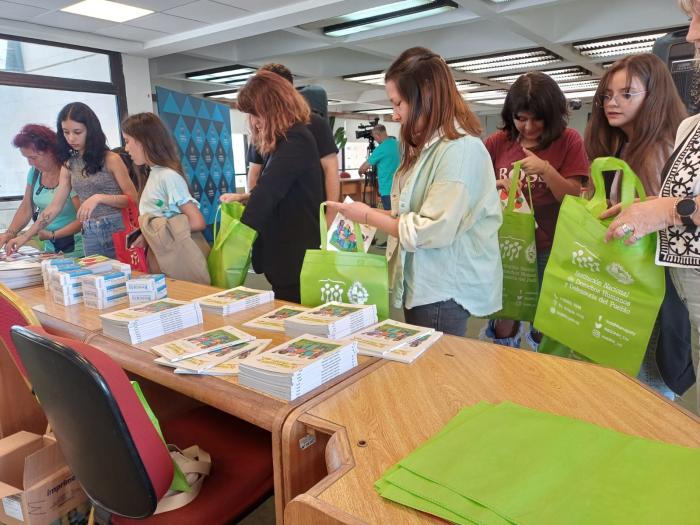 asistentes a la presentación tomando materiales de la mesa