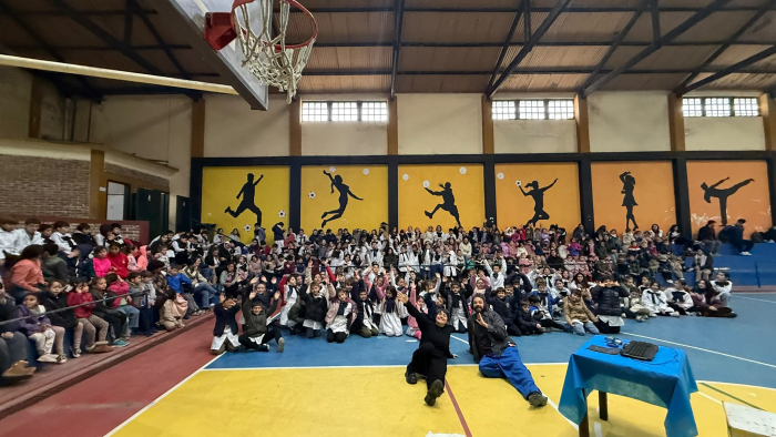 La actriz y el actor de la obra con los niños y las niñas de fondo La actriz y el actor de la obra están sentados en el piso y detrás está el público