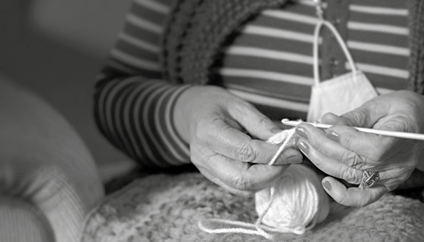 Manos de un adulto mayor tejiendo crochet