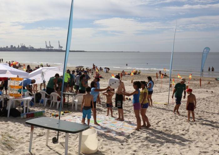 Público jugando con la rayuela interactiva en la playa. Sombrillas, flybanners y canchas de tejo