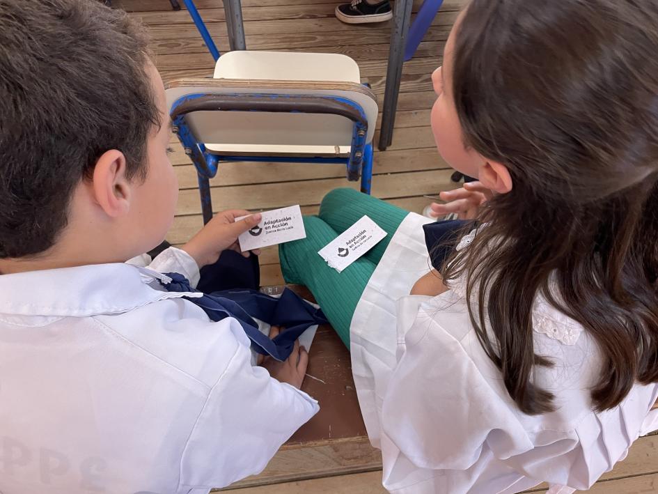 Niños con tarjetas del proyecto Adaptación en Acción que contienen semillas plantables