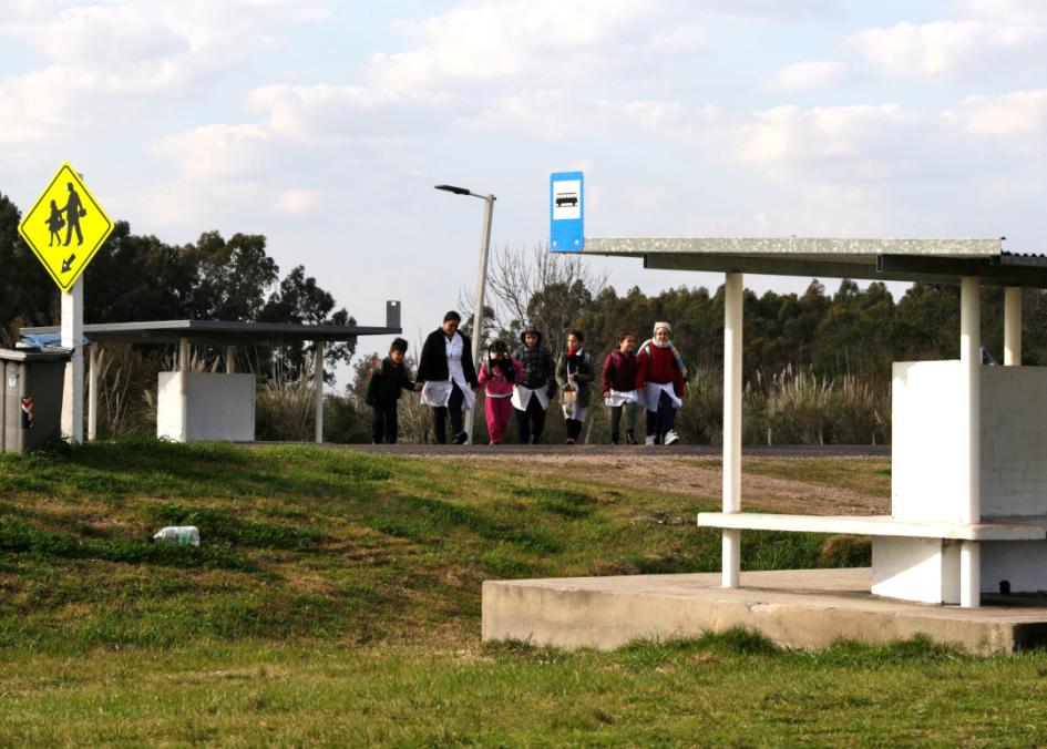 La maestra espera a los niños en la parada del ómnibus frente a la escuela