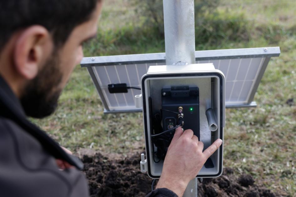 Un trabajador chequea la conexión del telepluviómentro al panel solar