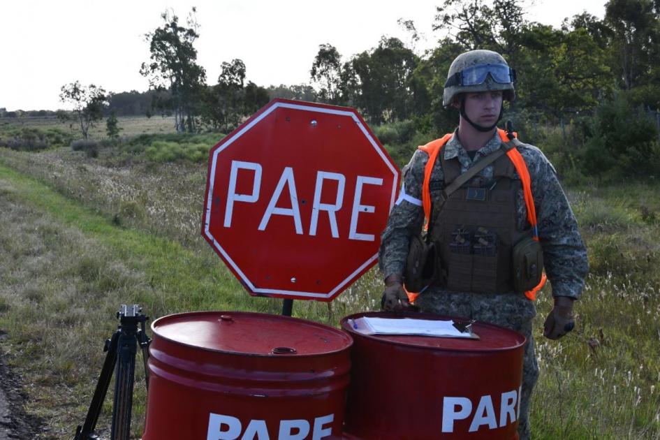 Patrullaje fronterizo Personal militar al lado de cartel de pare en puesto de control fronterizo