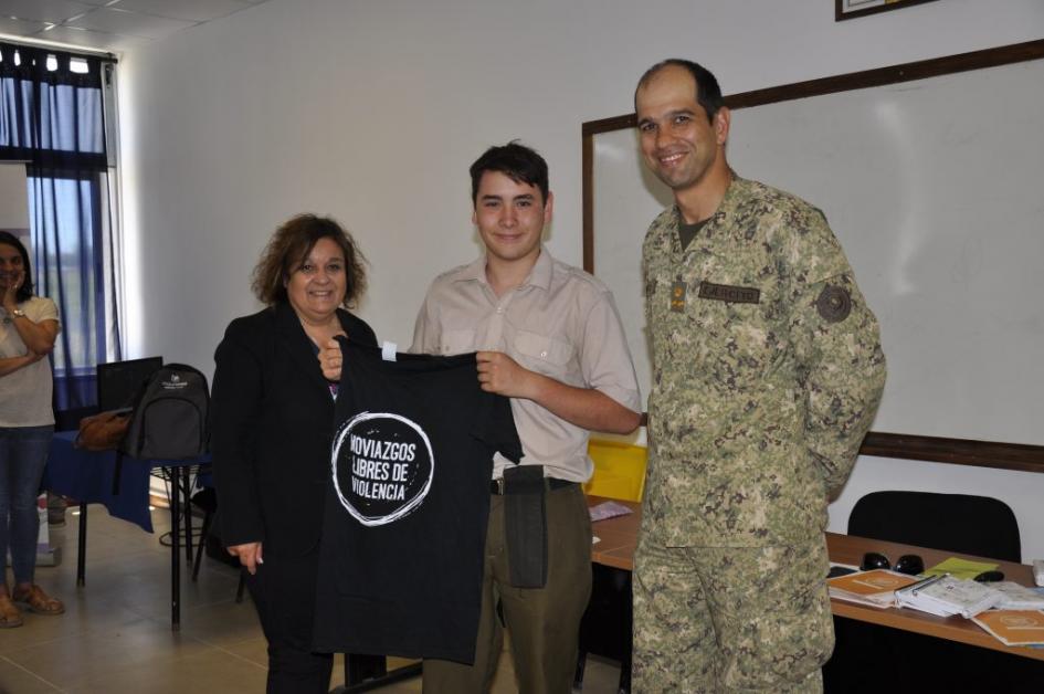 Integrante de Comisión de Género y Dtor. del Liceo con alumno del Liceo Militar sosteniendo una remera color negra con la leyenda Noviazgos Libres de Violencia