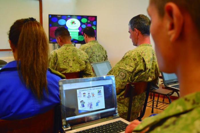 Alumnos sentados frente a computadoras en un salón de clases