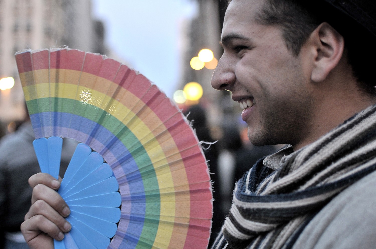 Hombre en desfile mueve un abanico con los colores de la Diversidad.