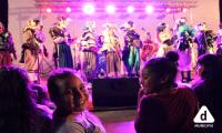 Club de Verano Cuenca Casavalle Tablado con murguistas y en primer plano una niña mira de frente a la cámara