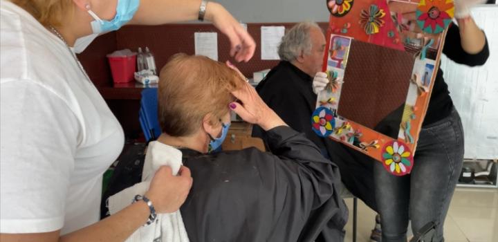 Mujer se mira al espejo con el cabello recién cortado por peluqueros solidarios