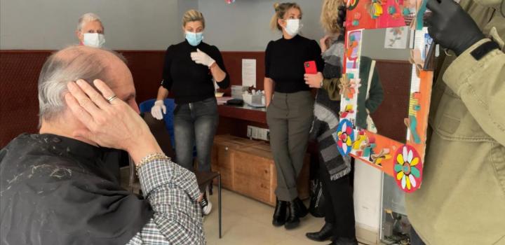 Hombre se mira al espejo luego de corte de cabello realizado en jornada solidaria