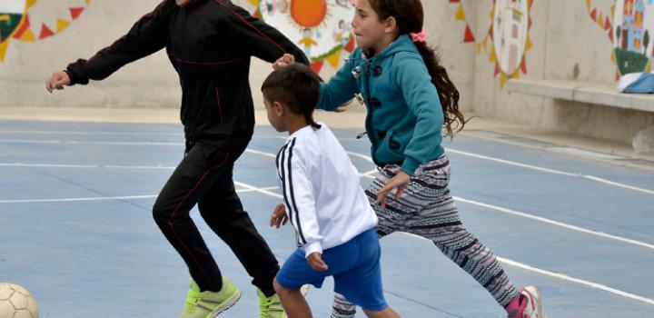 Actividad física Dos niños y una niña juegan al fútbol