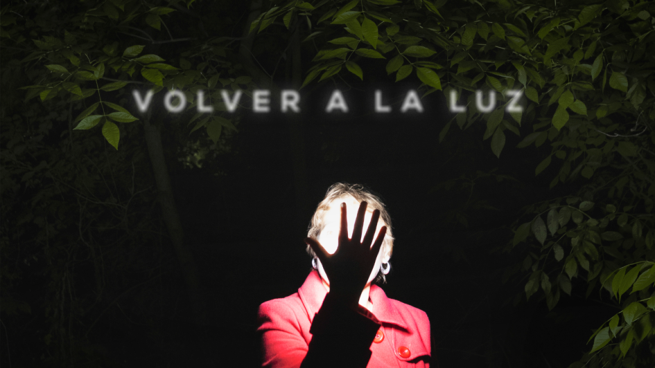 Afiche en el que se ve a una mujer parada en exteriores, de noche. Su mano tapa su rostro.