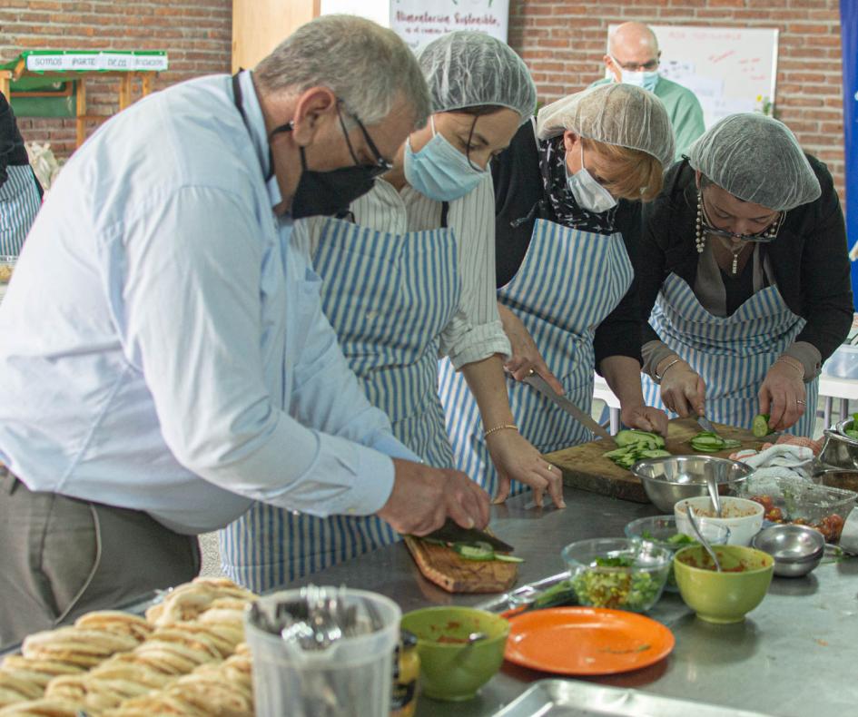 Personas cocinando en una mesa grande.