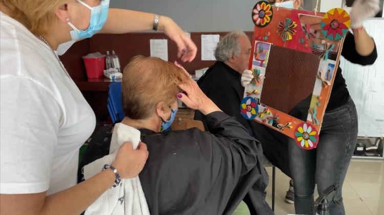 Usuaria del refugio Hotel Urban en jornada solidaria de corte de cabello Mujer se mira al espejo con el cabello recién cortado por peluqueros solidarios