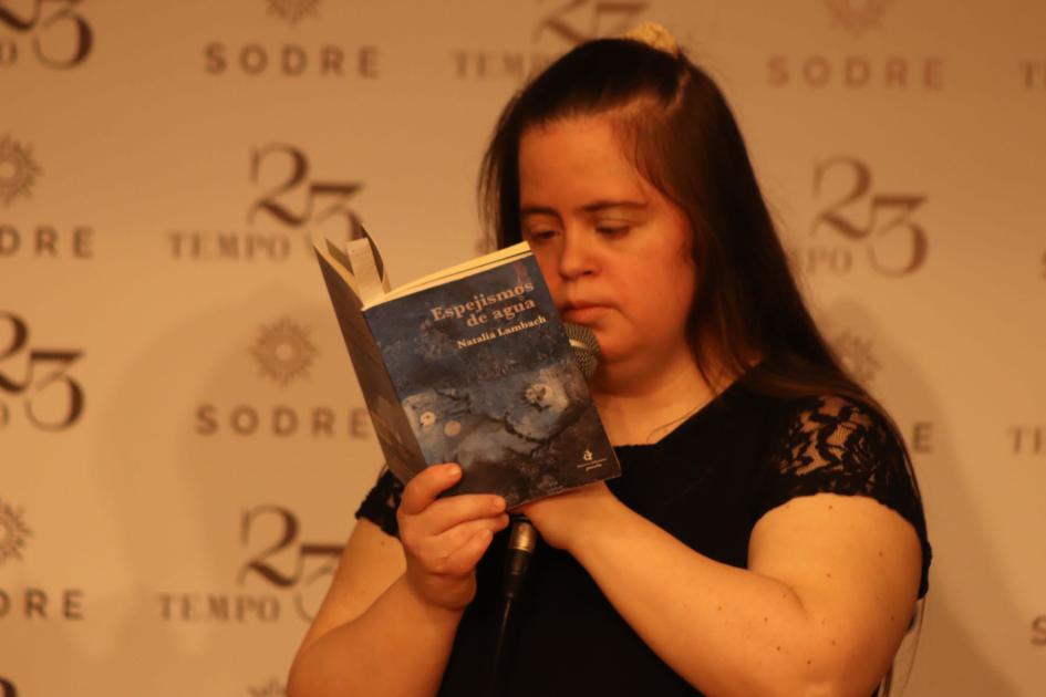 Mujer joven con síndrome de Down leyendo libro de su auditoría: "Espejismos de agua".