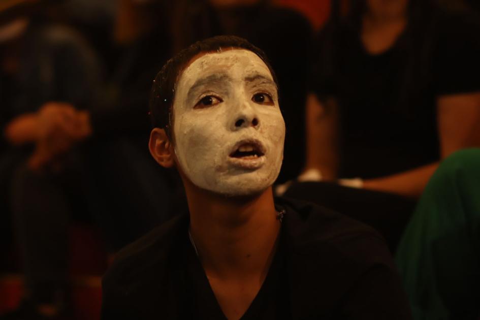 Muchacho joven con ropa negra y la cara pintada de blanco hace coreografía y expresión corporal.