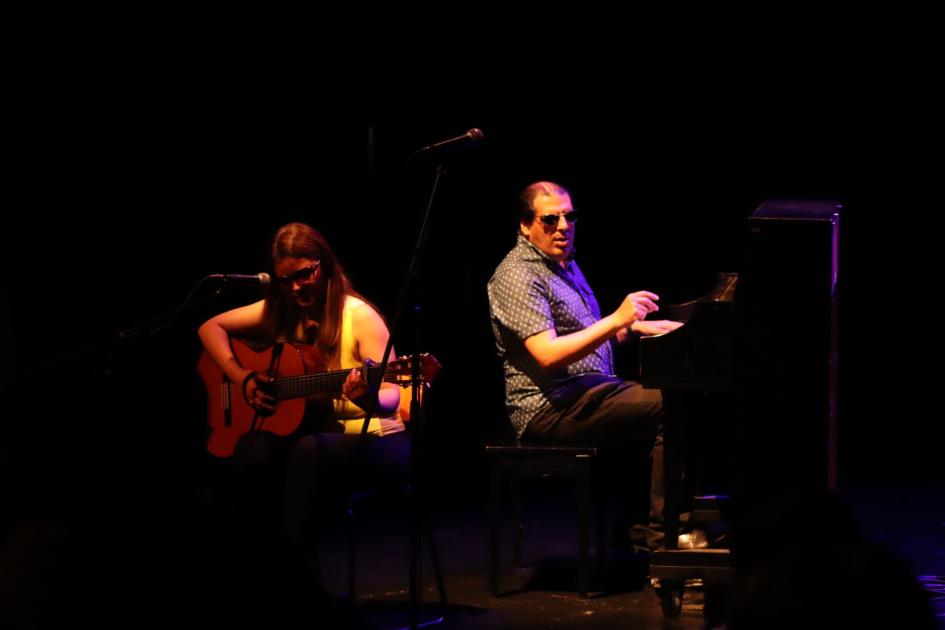 Ana Medina de Chuy, Rocha con la propuesta musical "Mi regalo", canto y guitarra. Mujer toca guitarra criolla y la acompaña hombre en piano, sentado detrás de ella.