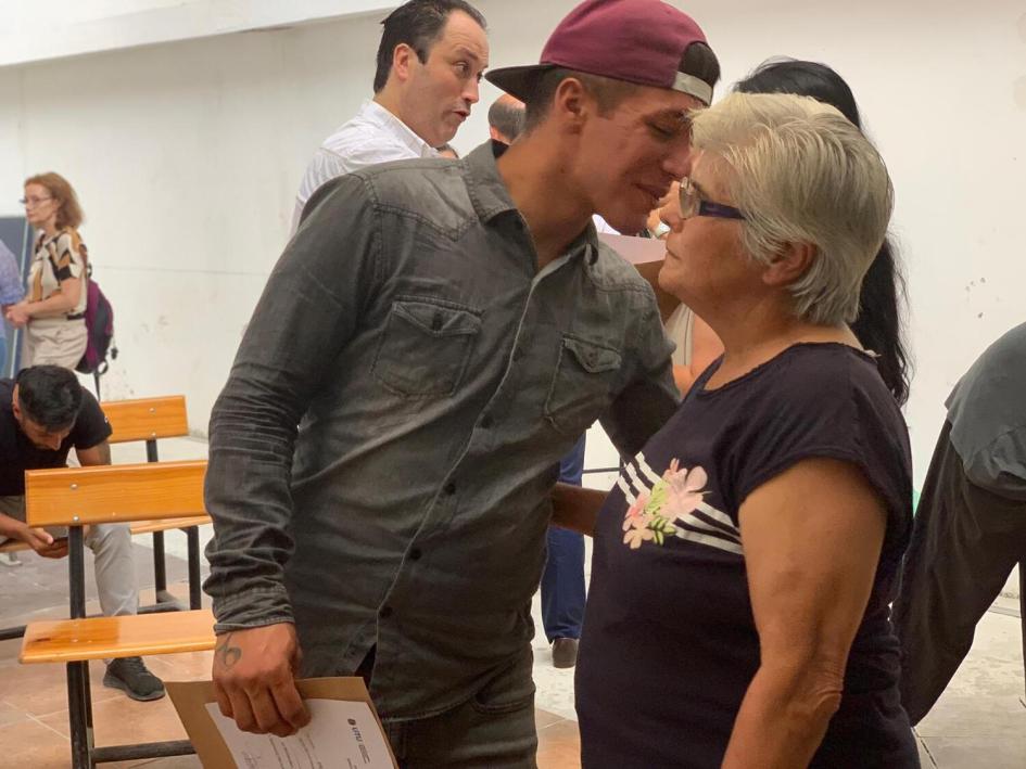 Estudiante saluda a la docente de Pañol. Hombre joven besa en la mejilla a la docente de Pañol