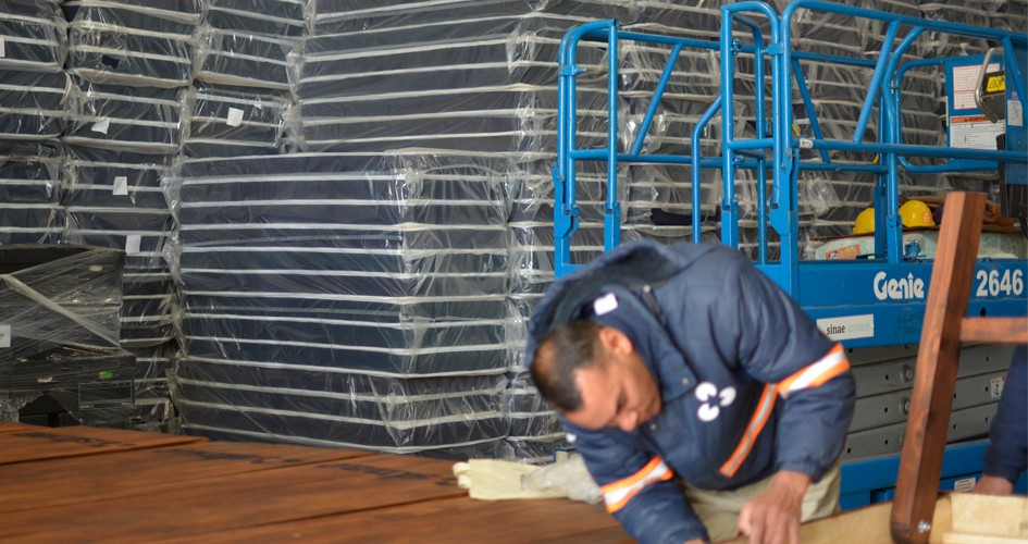 Persona con uniforme de Sinae trabajando con una pila de colchones de fondo