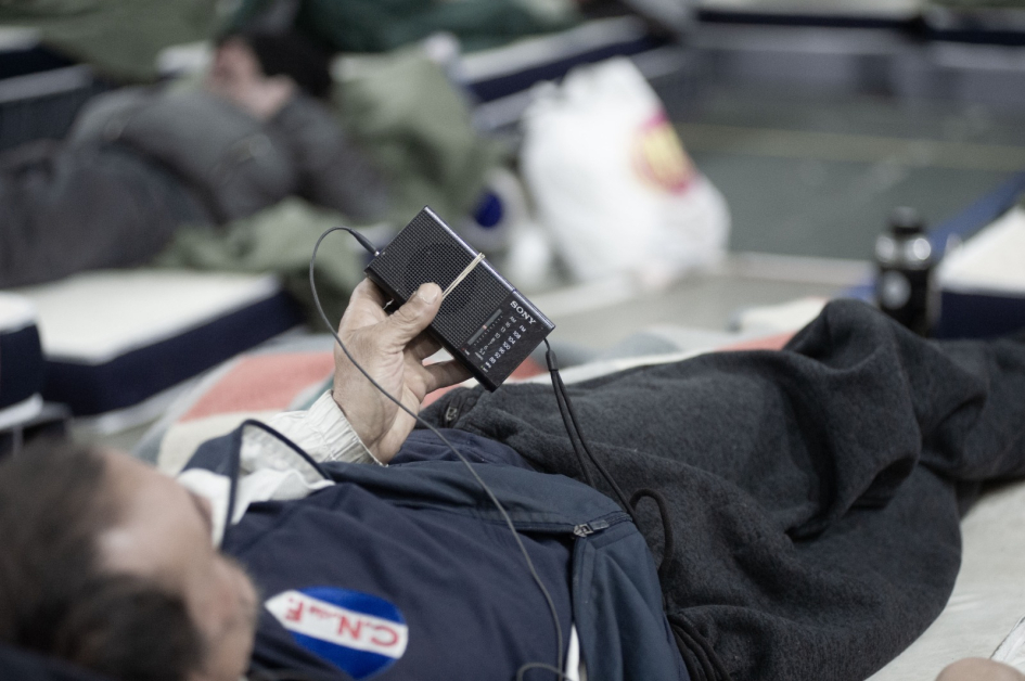 Persona sobre un colchón con una radio portátil en la mano Hombre acostado escuchando la radio