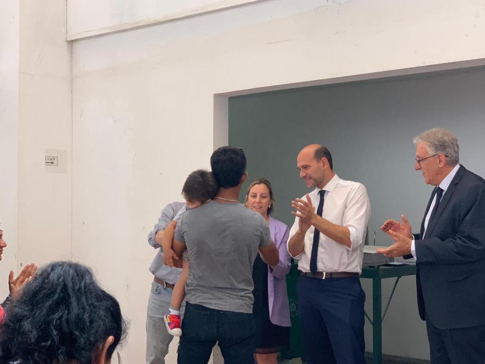 Autoridades de MIDES y UTU durante la entrega de certificados. Lema, Sena y director de UTU entregan diploma a hombre joven que tiene un niño en brazos.