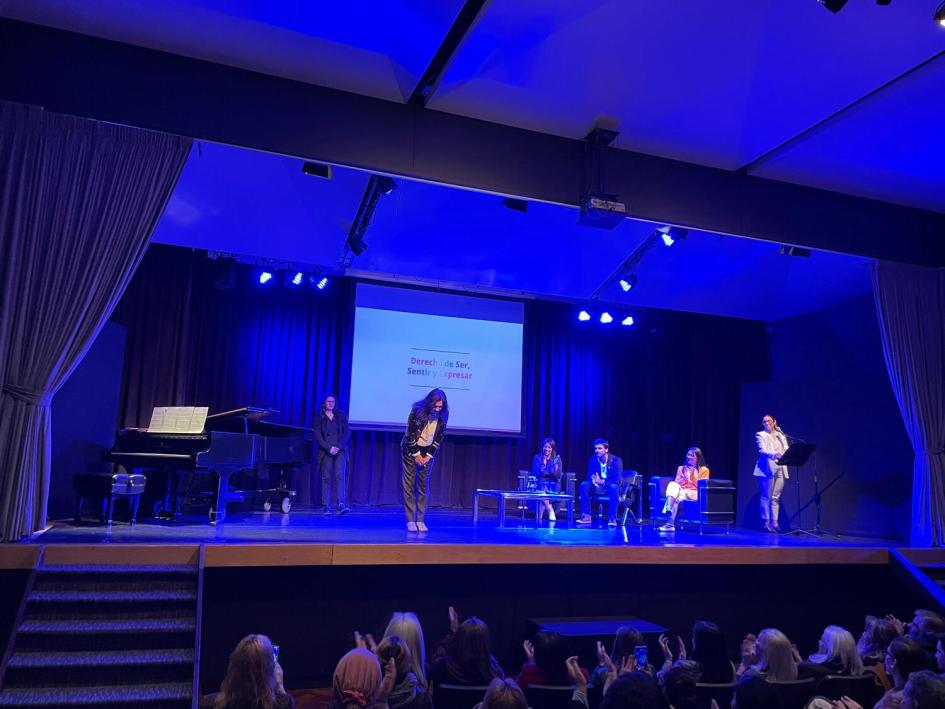 Carol Retamosa, pianista que dio la bienvenida y apertura al evento. Pianista de pie en reverencia al público, al fondo autoridades ministeriales.