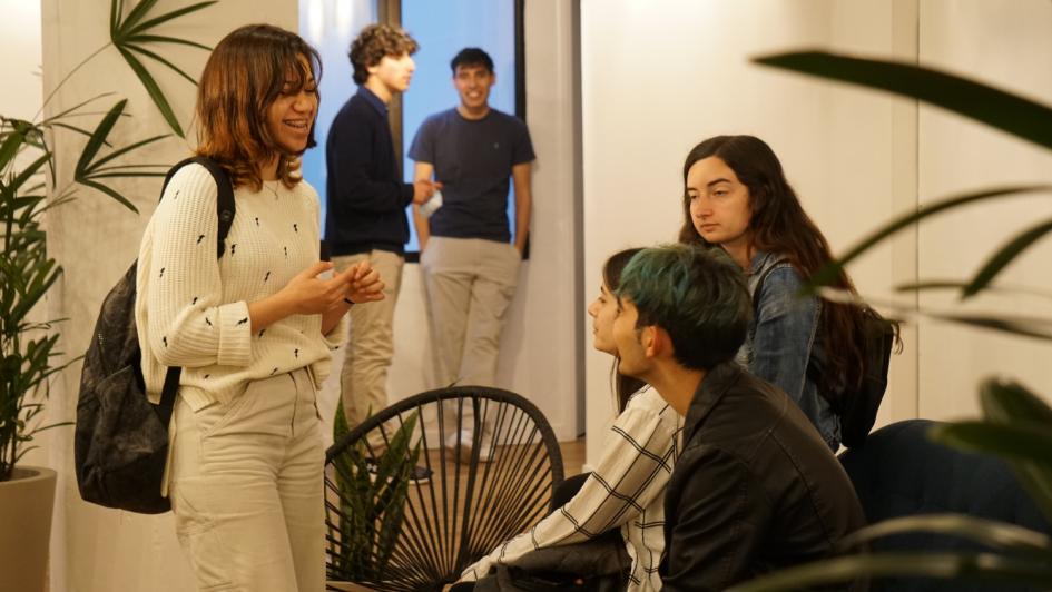 Reunión de jóvenes sentado y de pie rodeados de plantas en interior de la Ciudad Universitaria