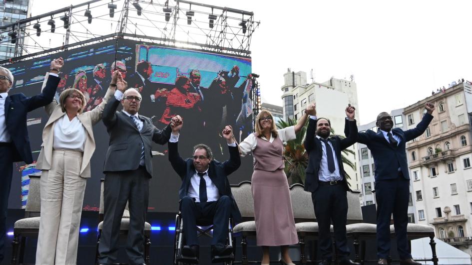 Ministras y ministro saludan desde el estrado al público presente en el acto Ministras y ministro saludan desde el estrado al público presente en el acto