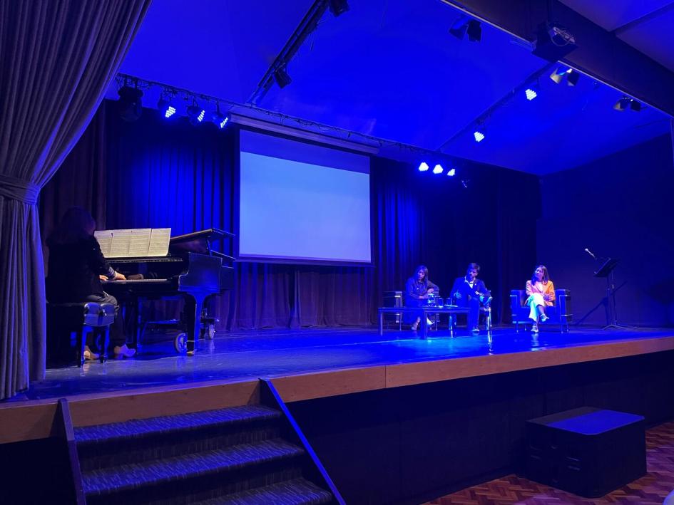 Apertura del acto lanzamiento del Mes de la Diversidad con repertorio de piano. Escenario, pianista tocando repertorio, pantalla gigante con logos. Tres autoridades en sillones.